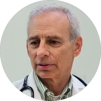 Senior male doctor in a white coat with a stethoscope around his neck, looking thoughtful.